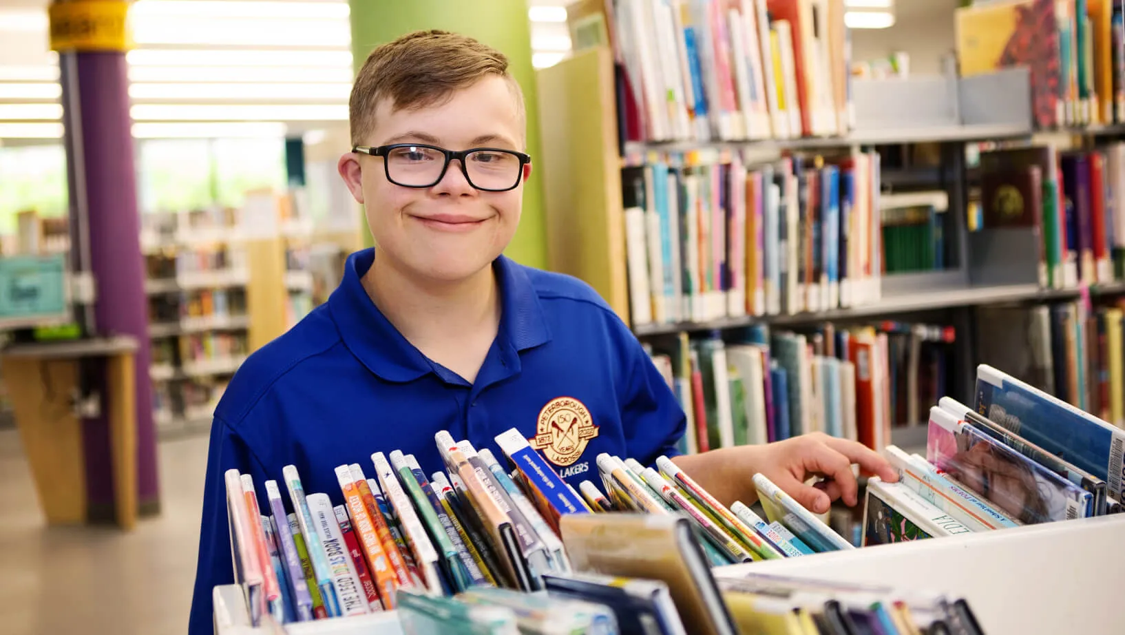 a smiling boy in front of books